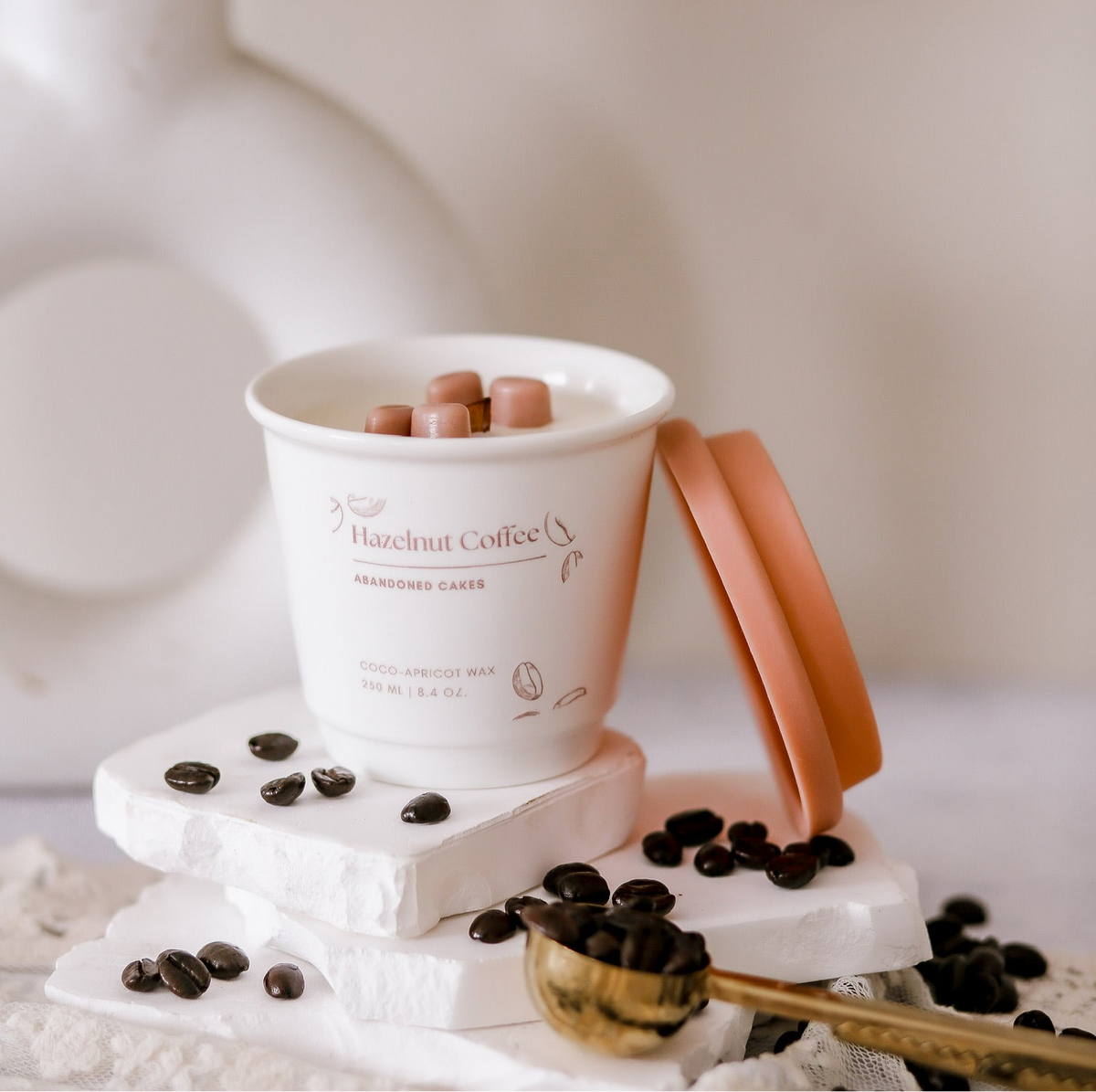 •	“Hazelnut Coffee Candle in ceramic to-go cup by Abandoned Cakes, surrounded by coffee beans and cozy textures”
	•	“Nutty coffee-scented candle with wooden wick and ceramic cup packaging”