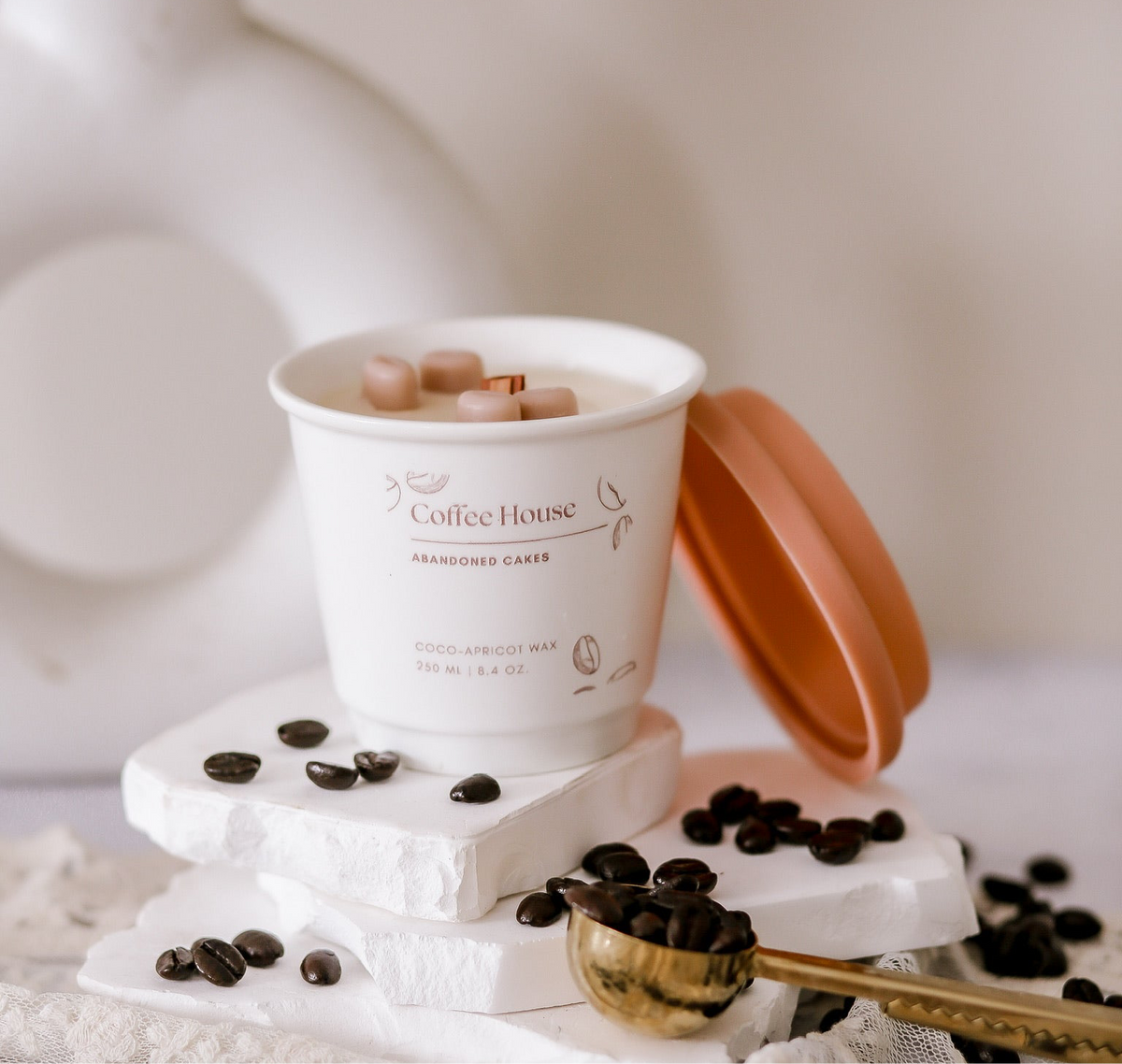 Hazelnut Coffee Candle in ceramic to-go cup by Abandoned Cakes, surrounded by coffee beans and cozy textures
Nutty coffee-scented candle with wooden wick and ceramic cup packaging